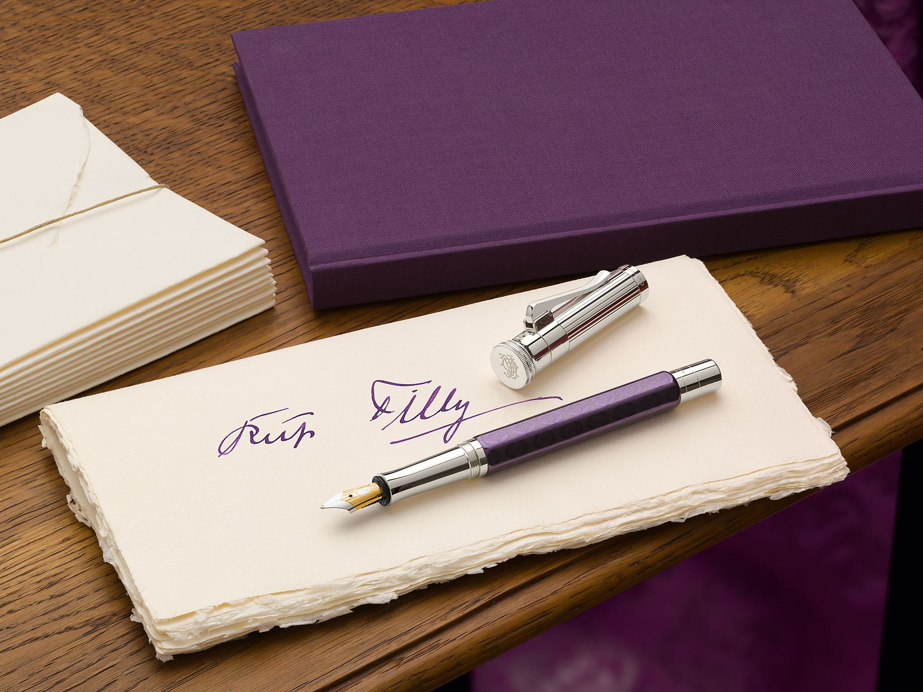 Das Bild zeigt eine handschriftliche Notiz "Für Tilly" in lila Tinte, zwei cremefarbene Umschläge und eine lila Schachtel.